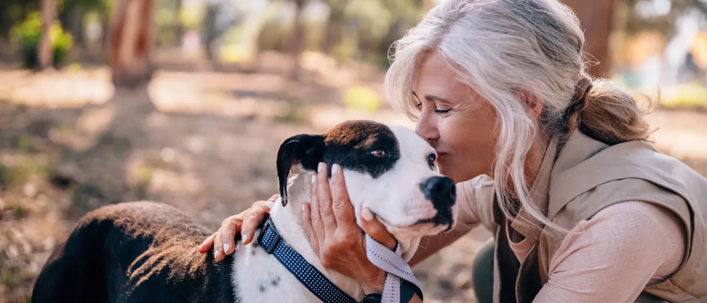 Woman kissing top of dog's head