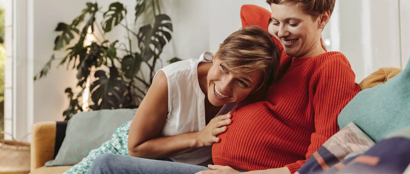 A pregnant woman sitting with her friend on a couch