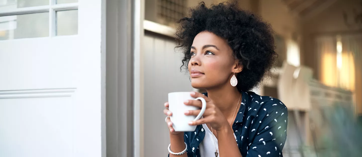 Woman sitting on her front steps drinking coffee
