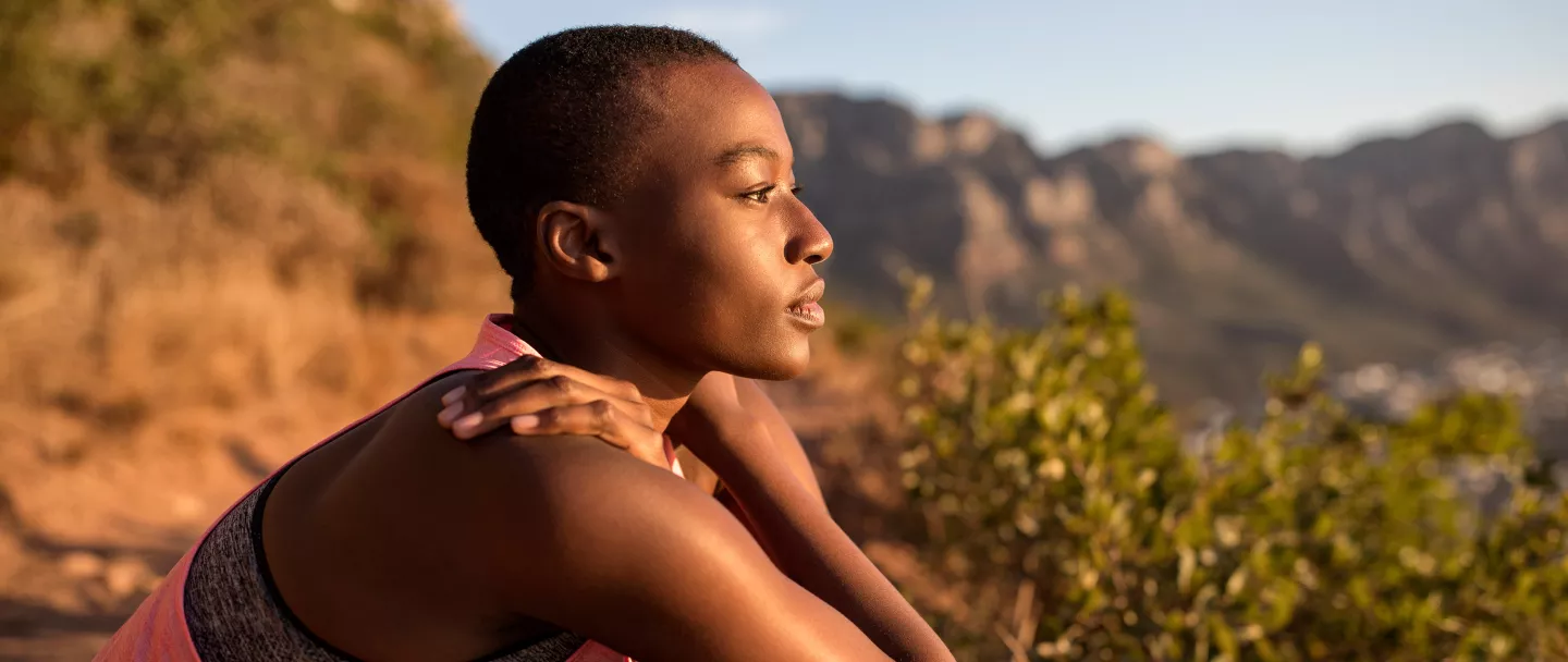 A young woman taking a break on a hiking trip, looking at the view.