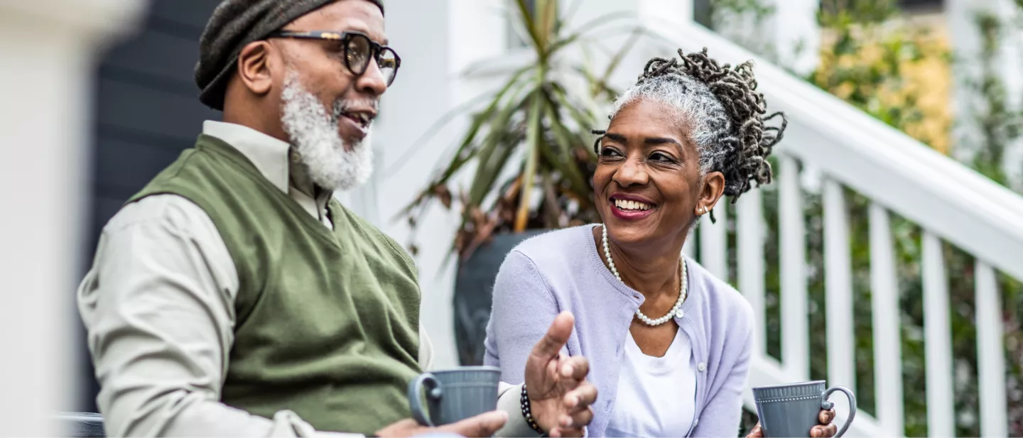 Two friends drinking coffee together sitting on steps of home