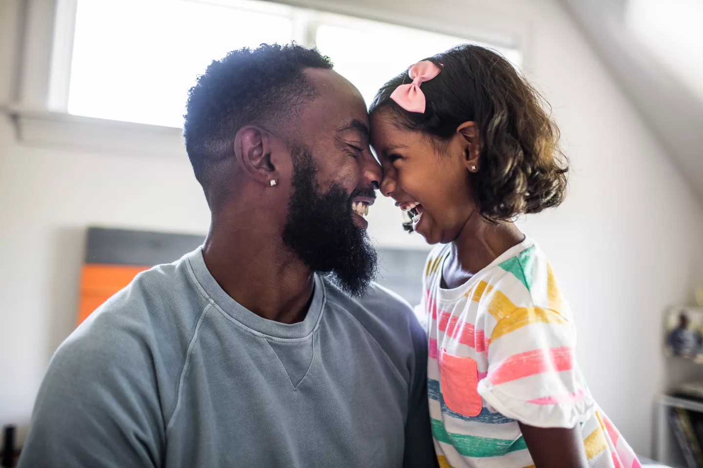 Father and daughter laughing at home touching noses