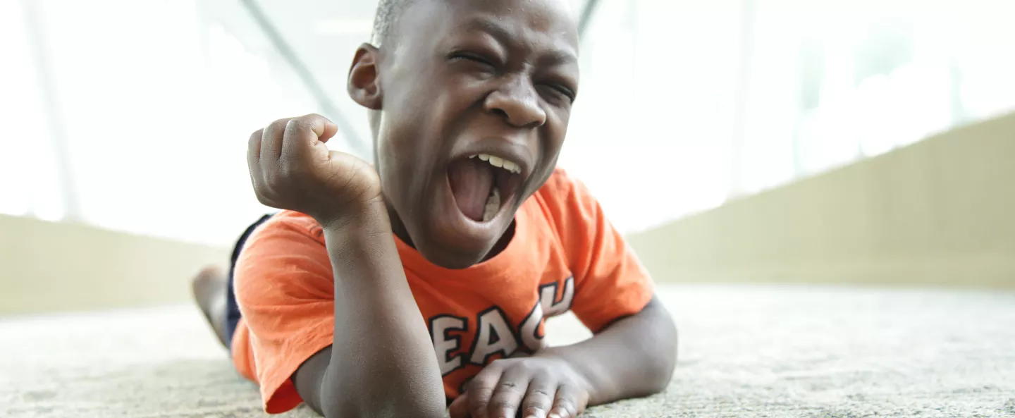 A boy laying on the floor smiling and laughing