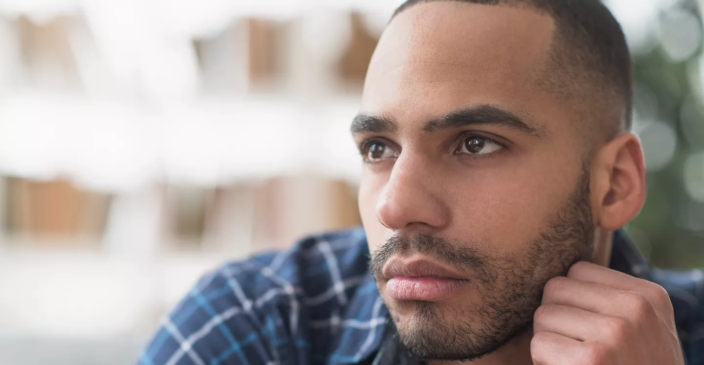 Close-up of a man in a plaid shirt looking thoughtfully into the distance