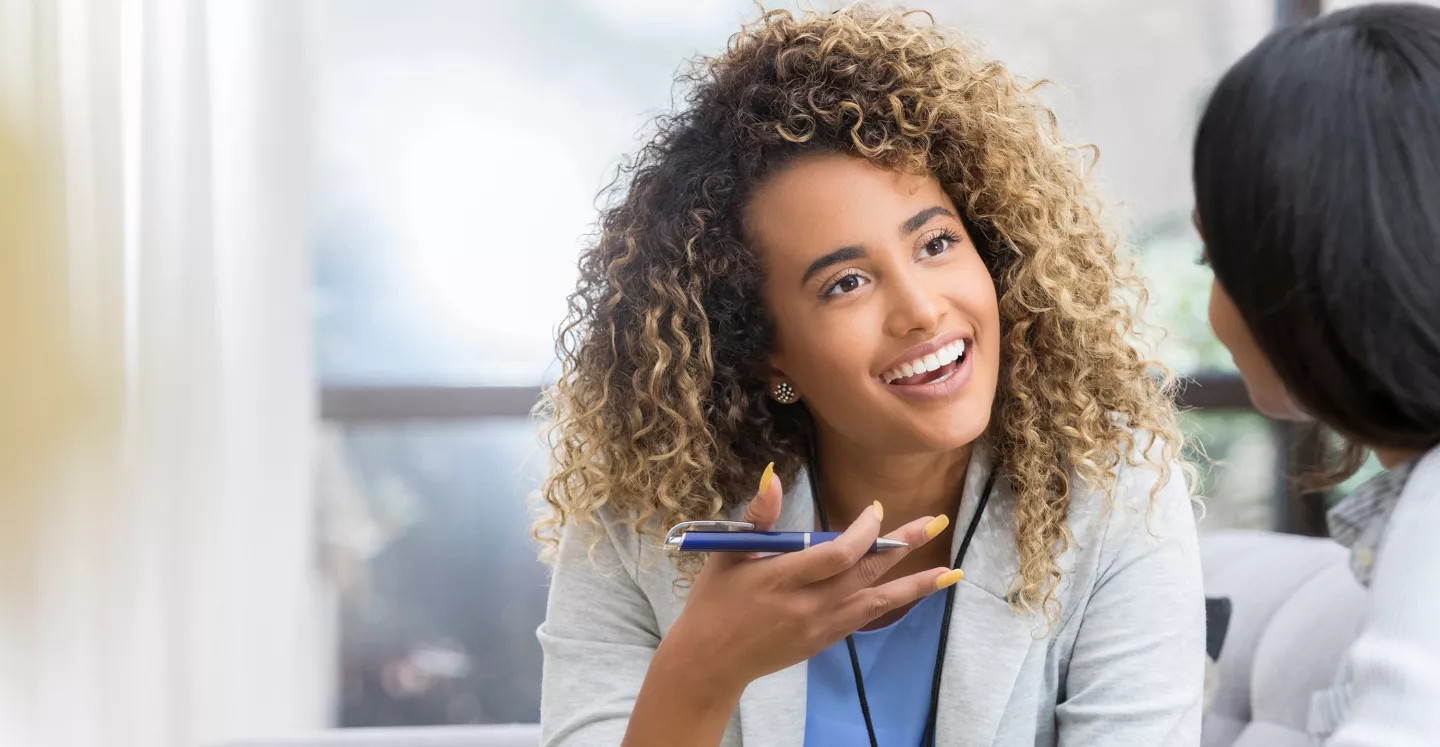 Woman smiling and talking with a pen in hand