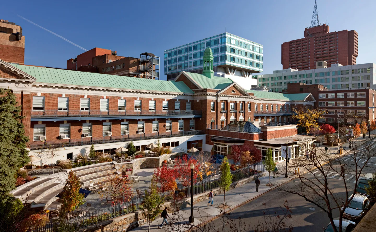 Exterior view of a medical campus with historic red brick buildings and a modern glass structure behind.