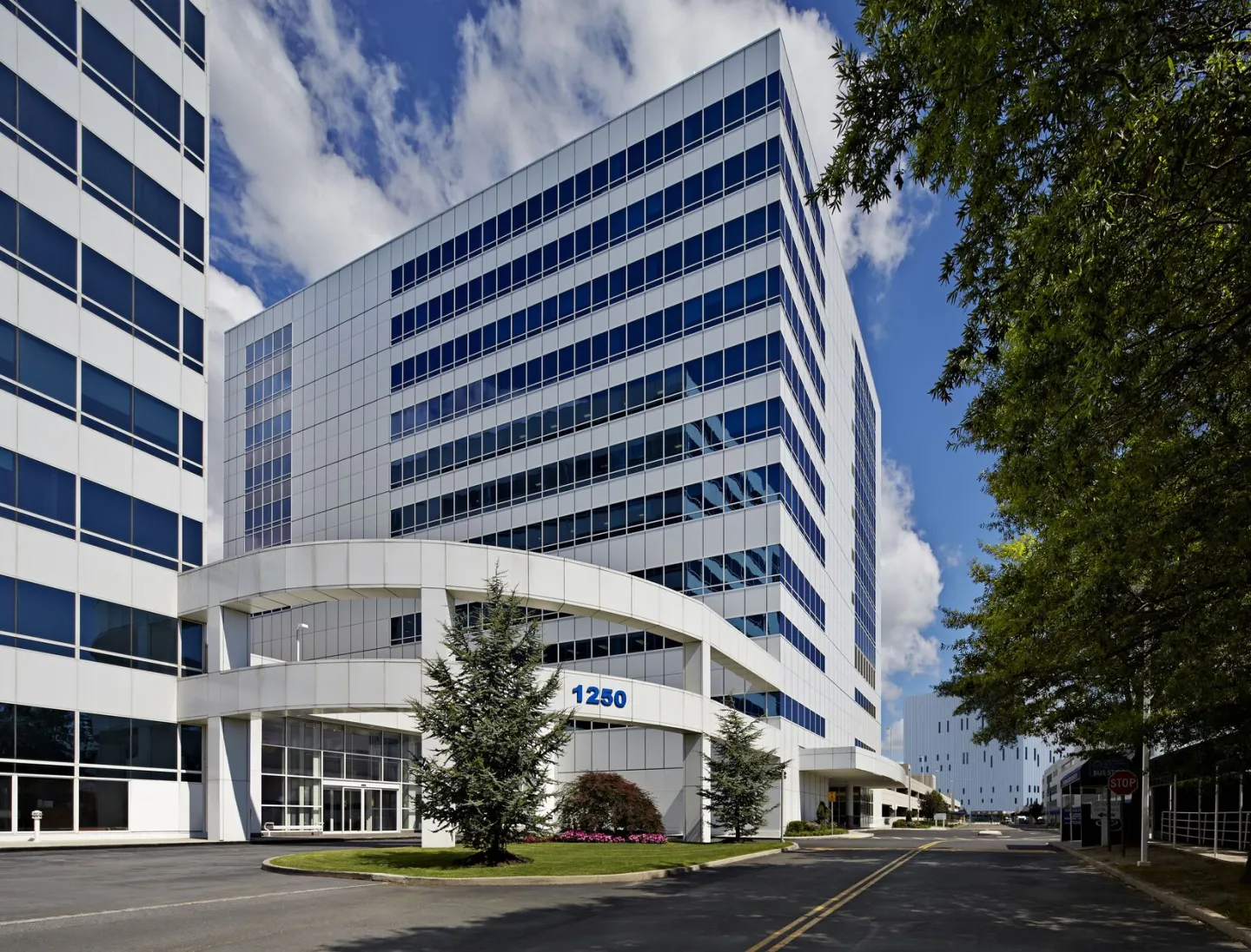 Modern exterior view of Montefiore Hutchinson Campus building, with reflective glass and tree-lined street.