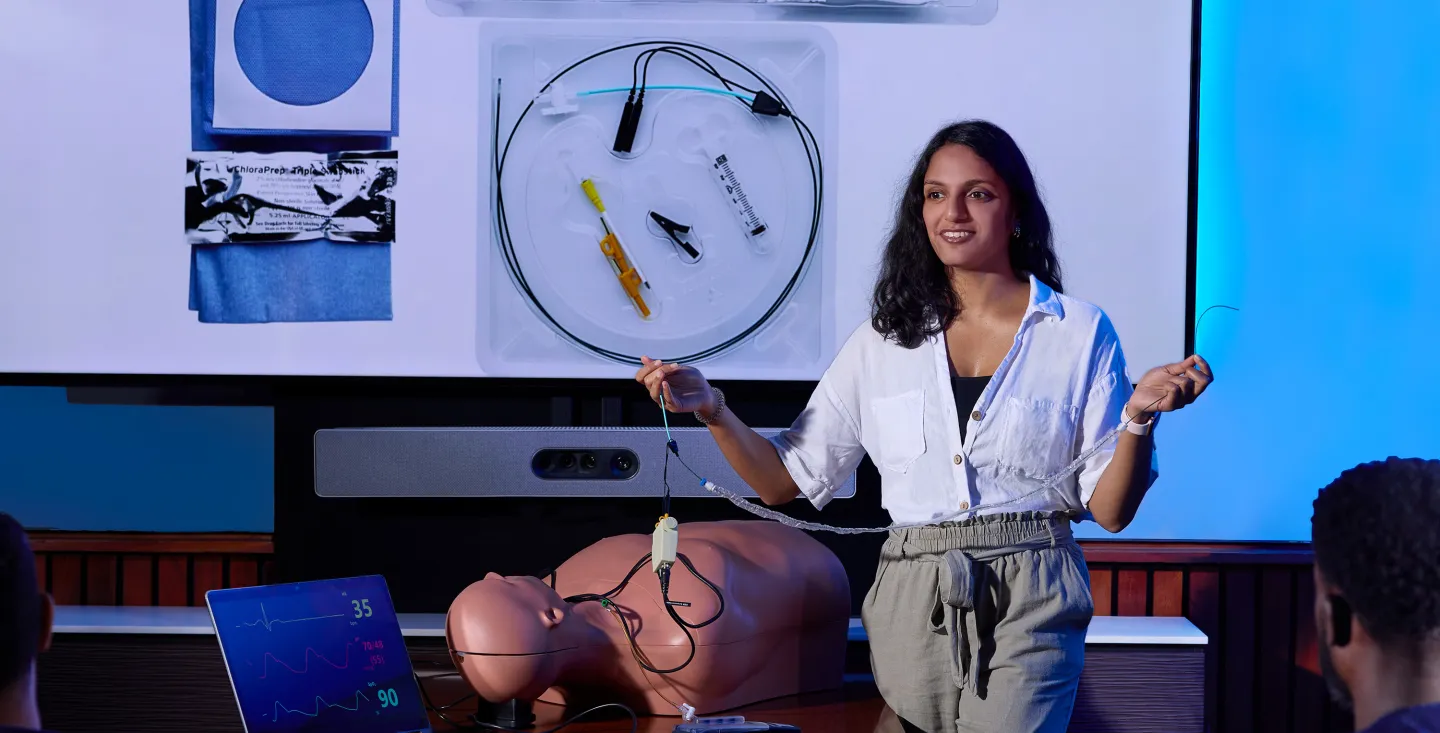 Medical educator demonstrating the use of a central line kit and guidewire during a hands-on emergency medicine training session with a mannequin.