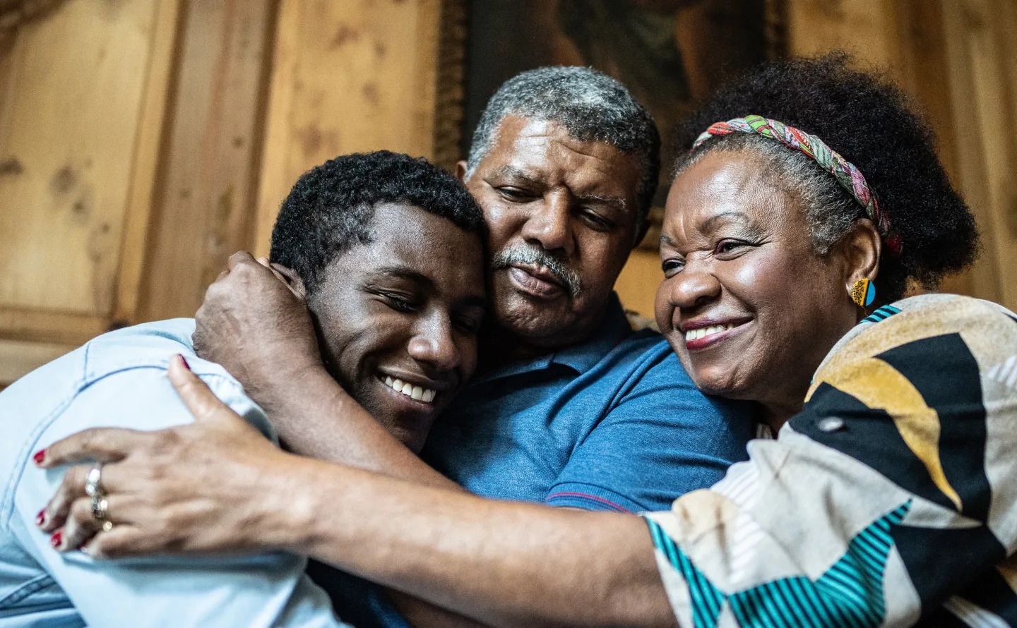 Young man embracing his parents in a warm and joyful family hug