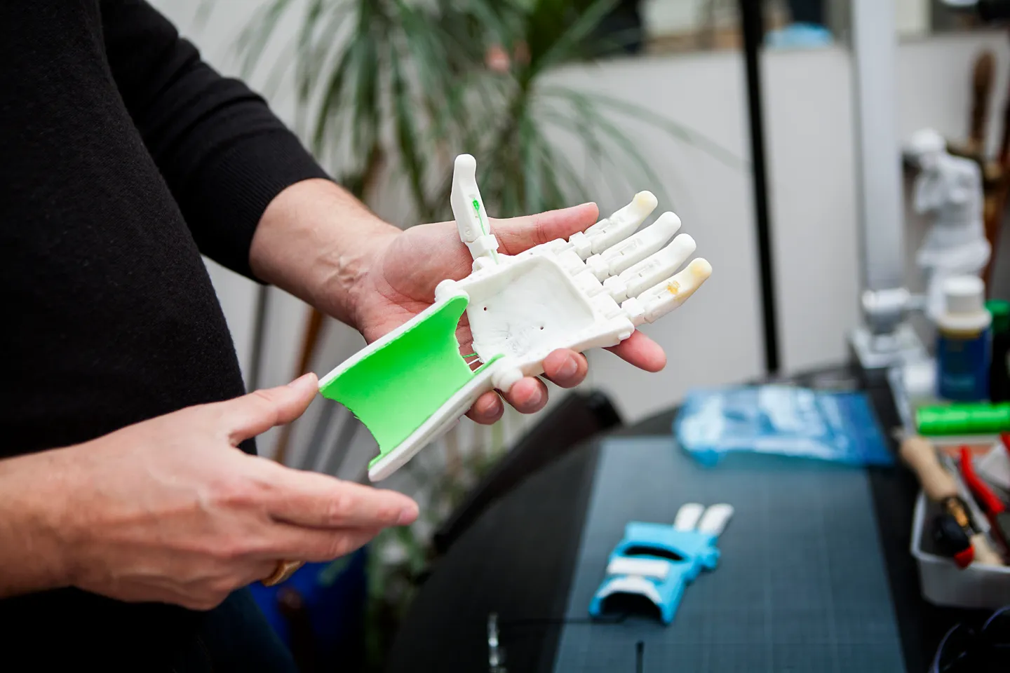Person holds a 3D-printed prosthetic hand with green and white components