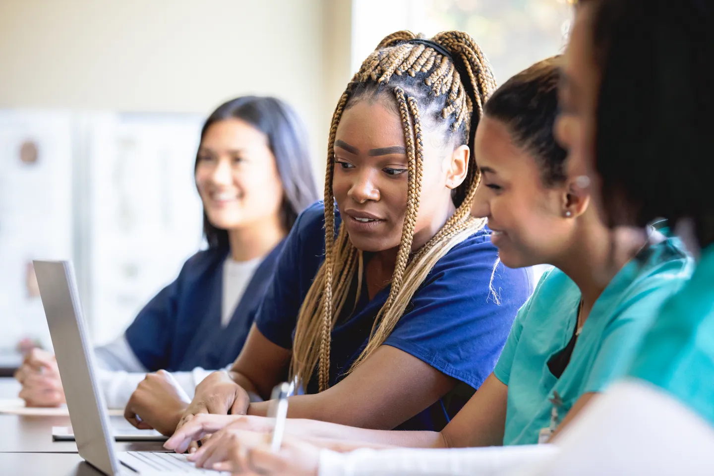 Group of nursing students in scrubs collaborate and take notes during class