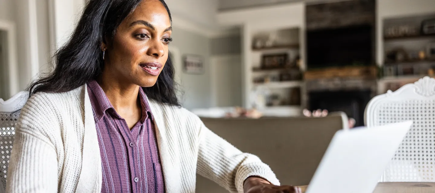 Woman sitting at a table with her hands on a laptop keyboard