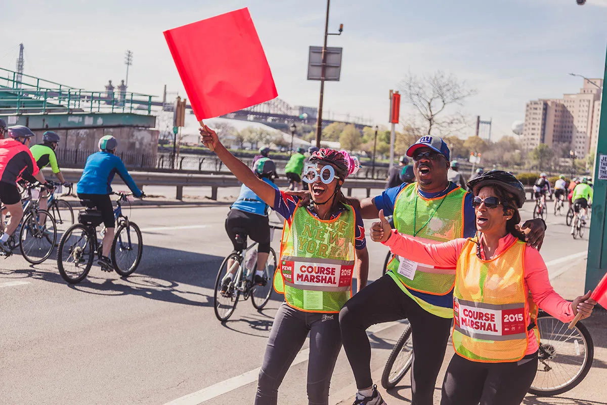 race marshals vawing flags as bikers ride past on bicycles