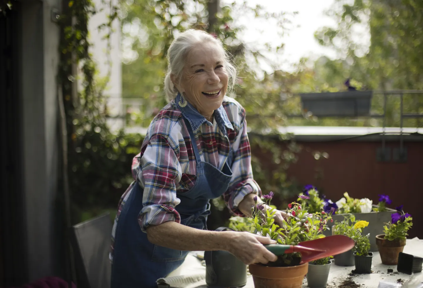 Elderly woman smiling while gardening on a balcony