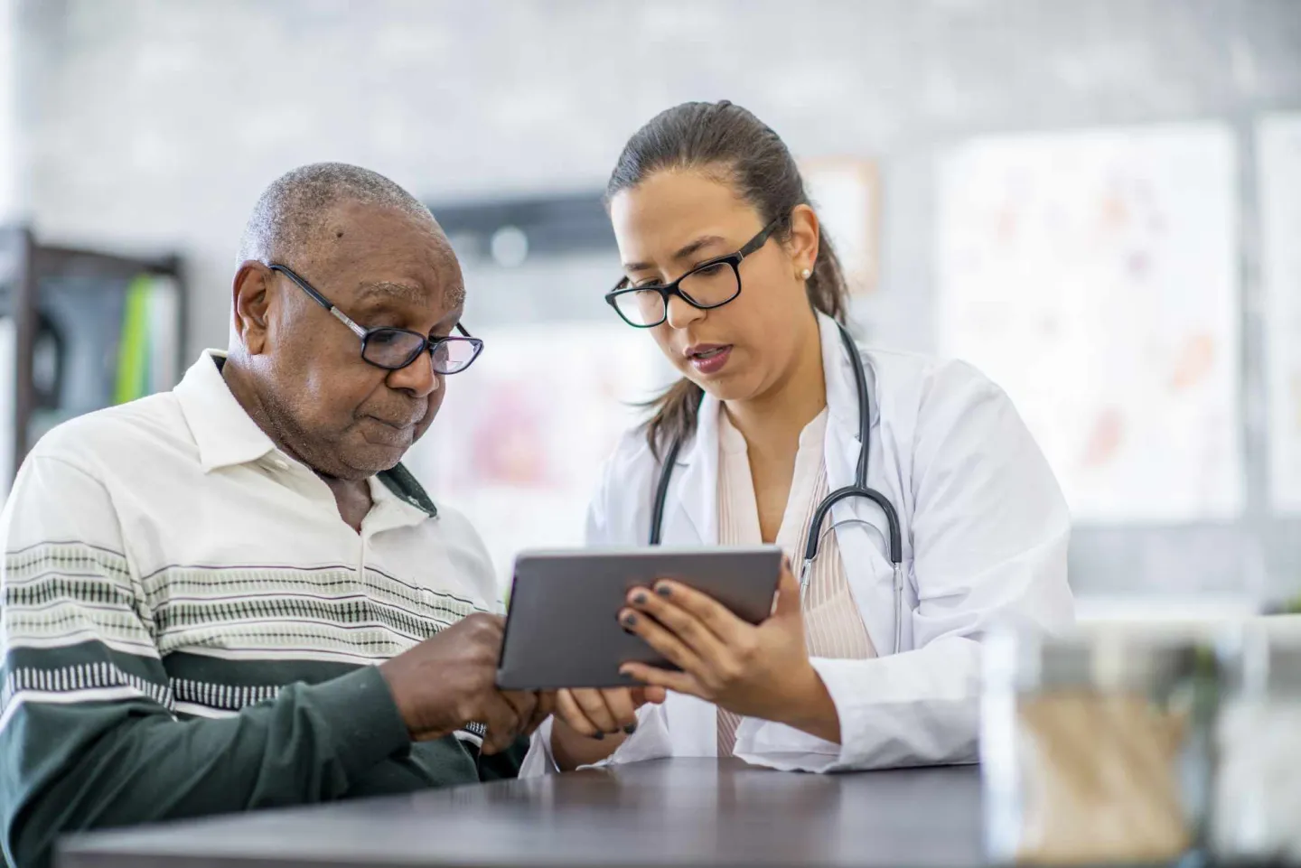 Female doctor showing an elderly male patient something on a tablet