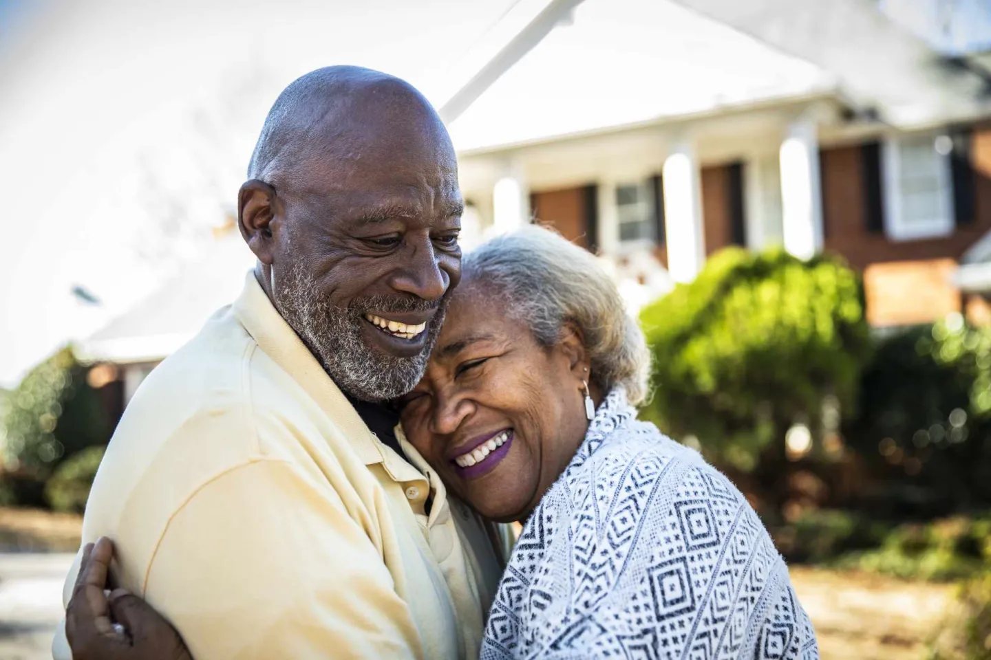 Elderly man hugging an elderly woman while both are smiling