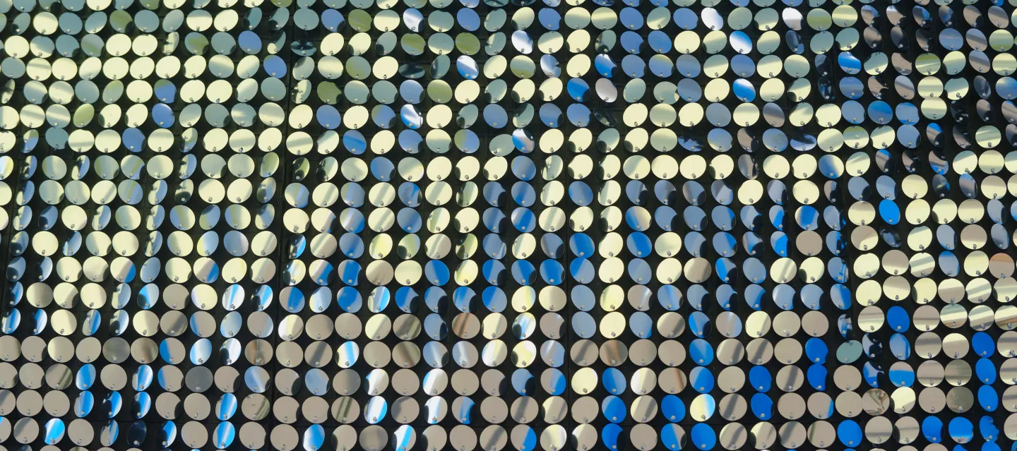 Image of small round mirrors arranged in rows and columns on a black background that sparkle and glitter.