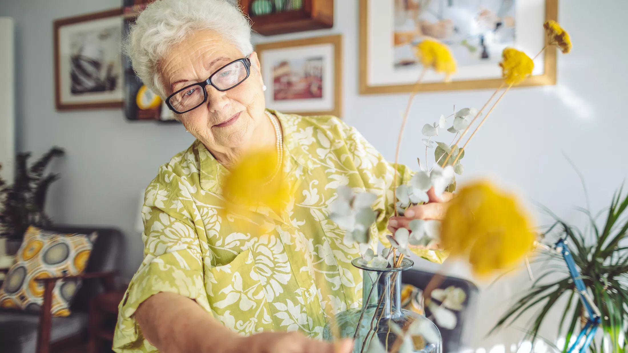 A senior woman tending to flowers inside her house