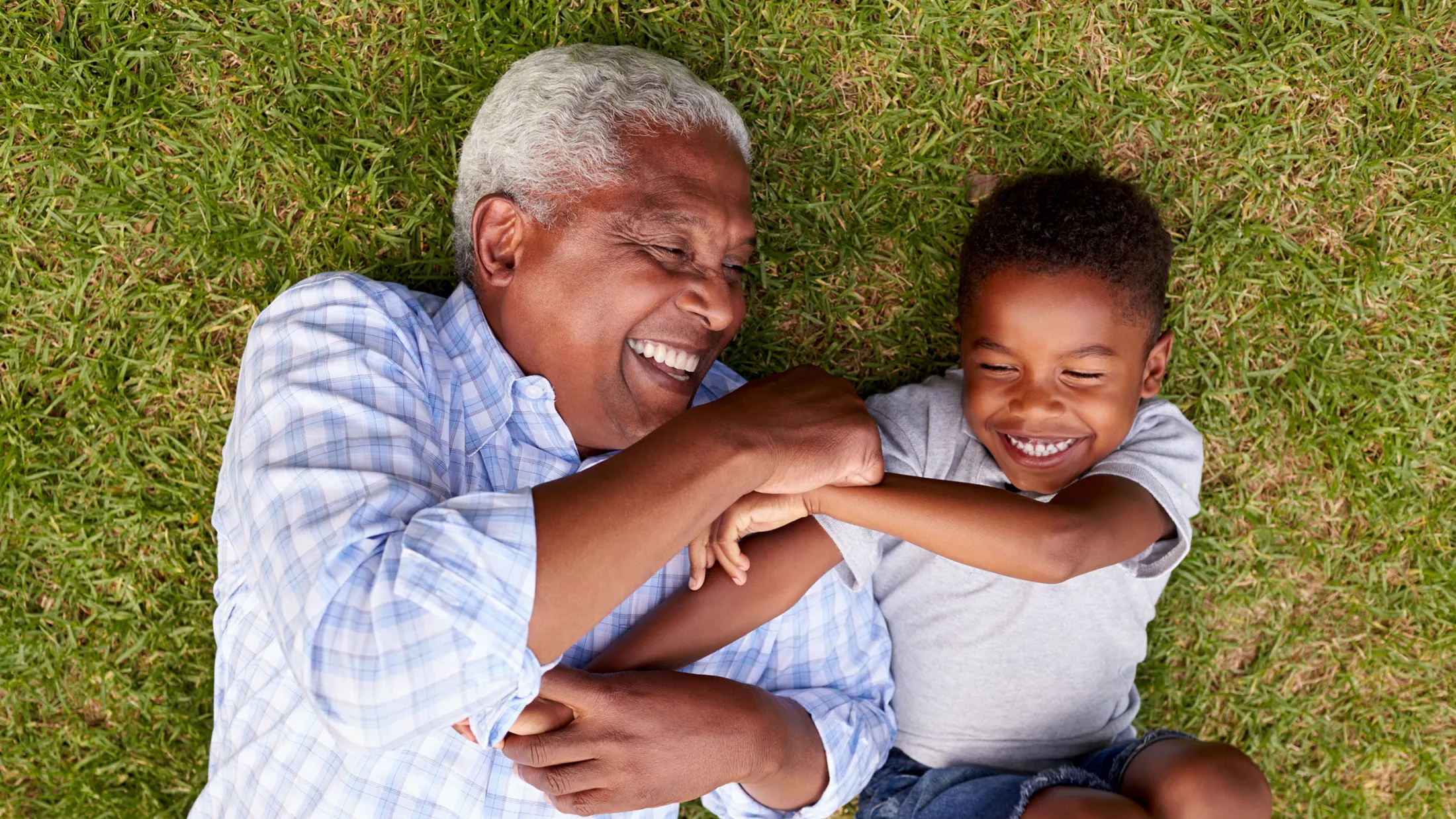 Grandfather and grandson playing on the grass