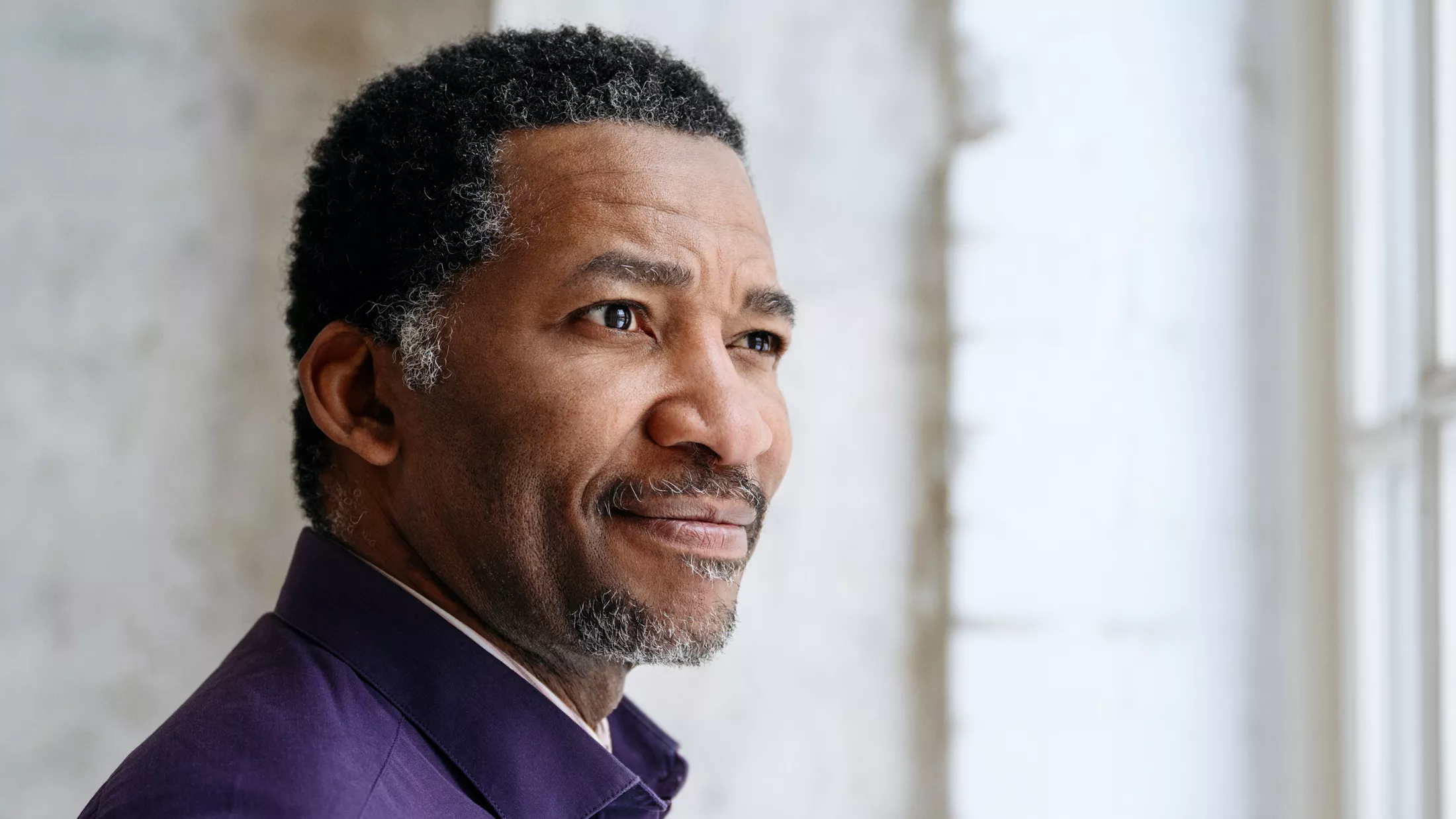 An older man thinking while looking out a window