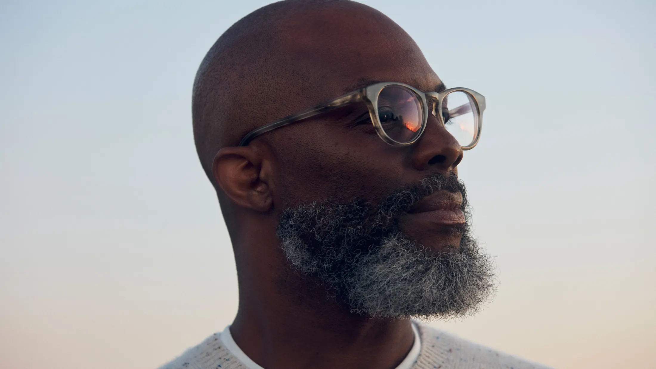 Man gazing into distance during sunset, calm and hopeful expression