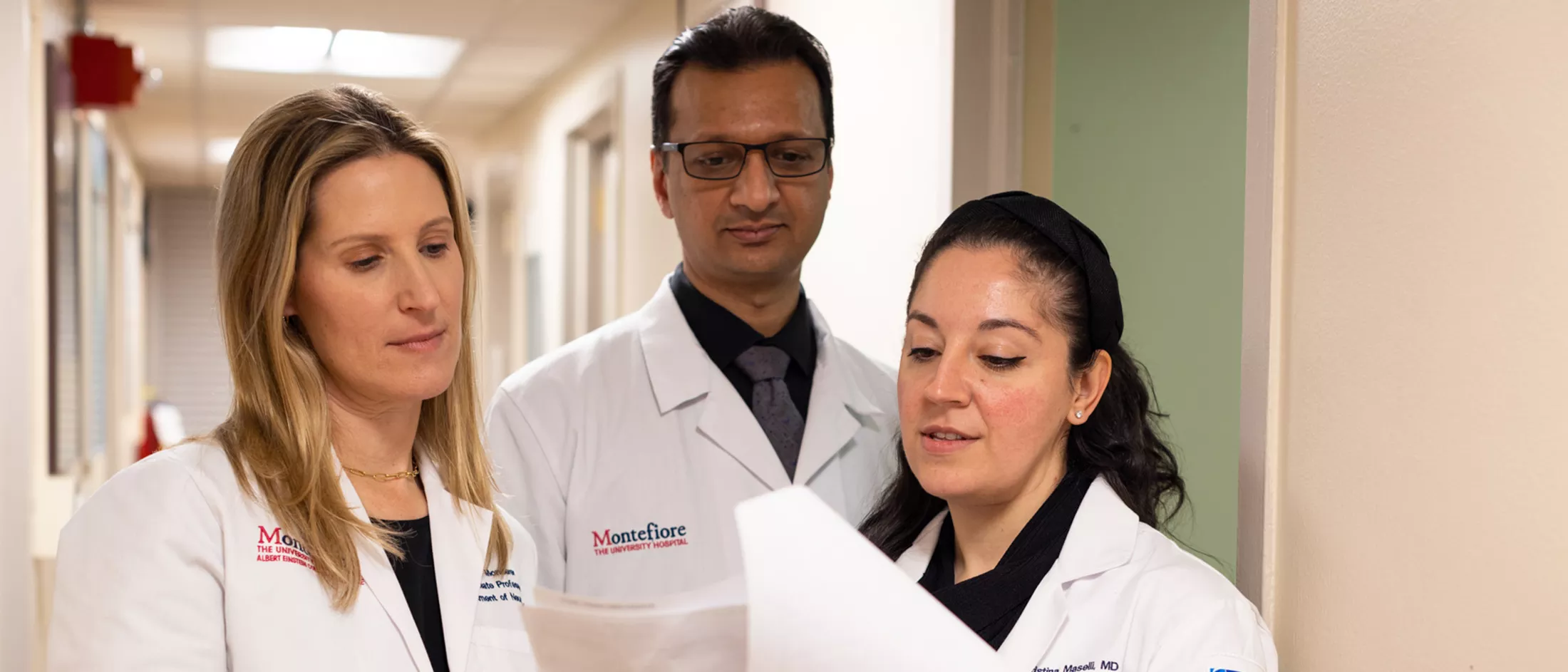 Three residents looking a document in a hospital hallway