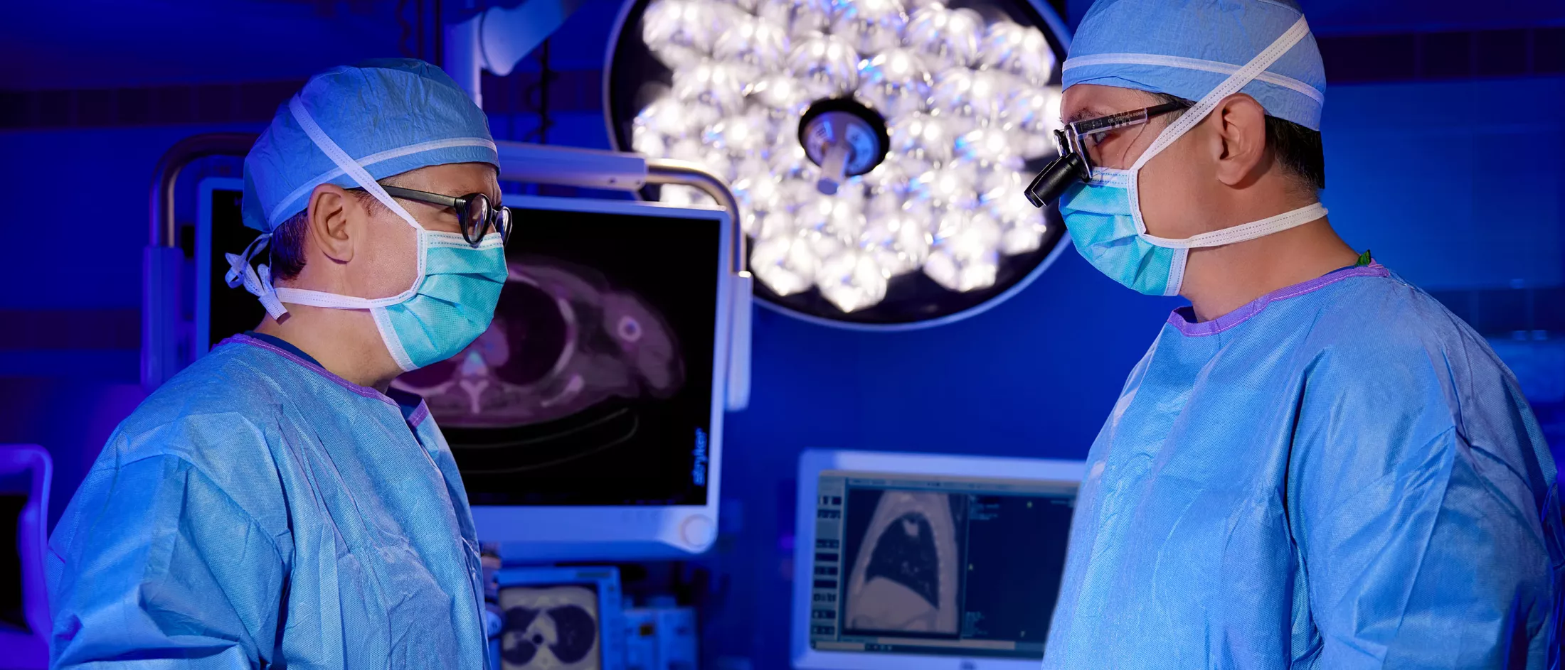 Two surgeons conversing in a hospital operating room.