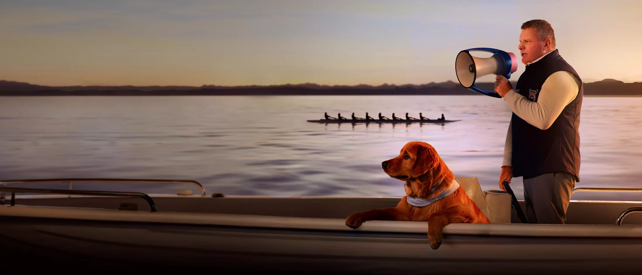 Guy Monseair holding megaphone coaching rowing team on lake with dog