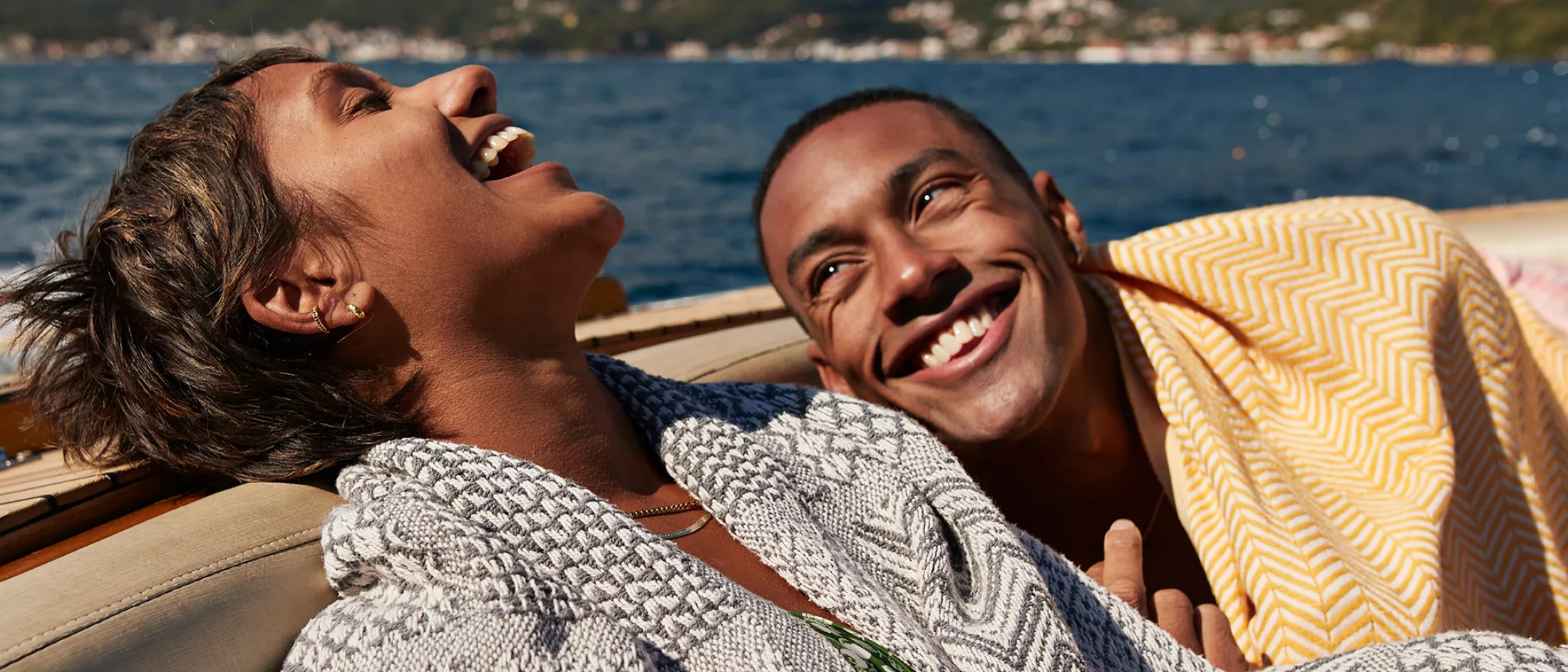 Young man and woman laughing in speedboat enjoying summer on sunny day