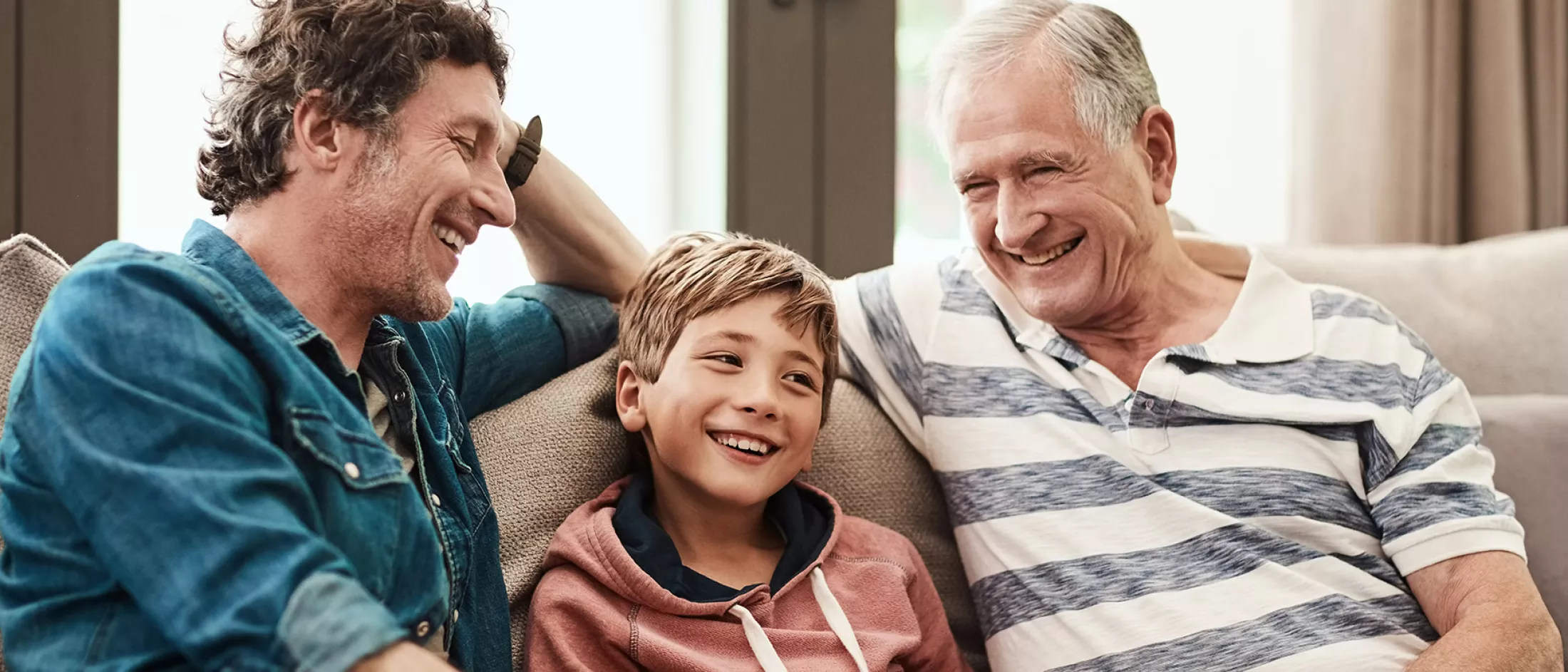 A grandfather, father, and son sitting on the couch