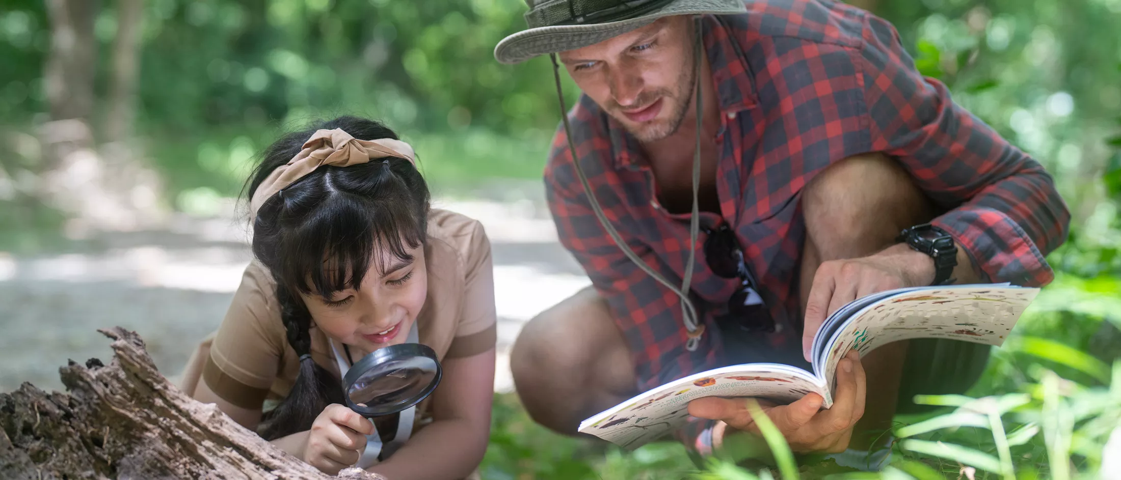 A father and daughter looking a insects through a magnifying glass