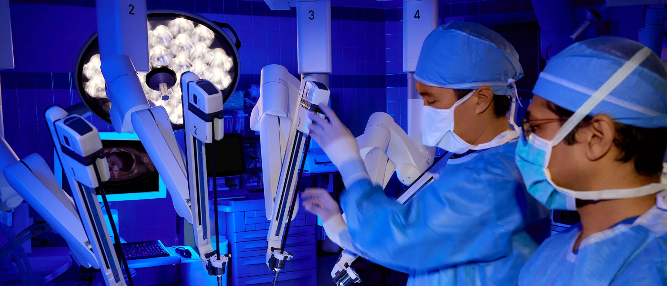 Doctors dressed in scrubs and masks work with surgical equipment.