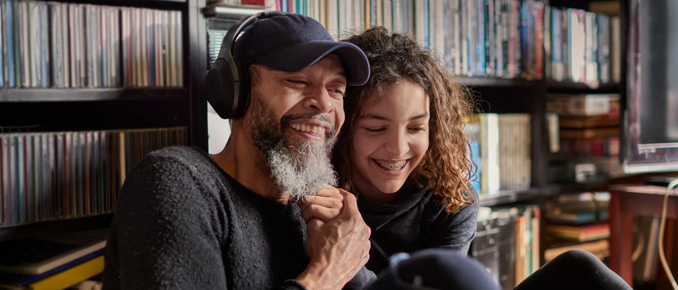 Father and teenage daughter sitting together and smiling in a cozy room
