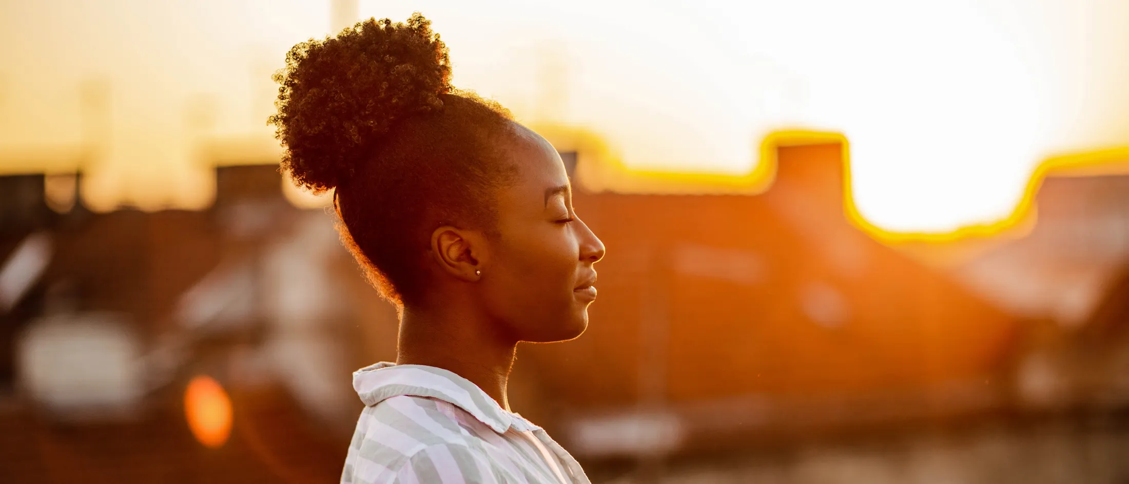 Woman meditating peacefully at sunrise on urban rooftop