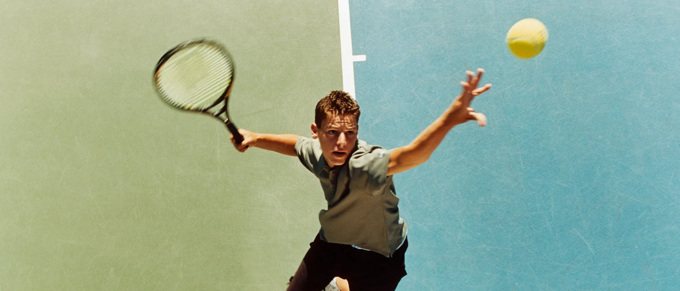 Young athlete jumping to hit a tennis ball mid-air.