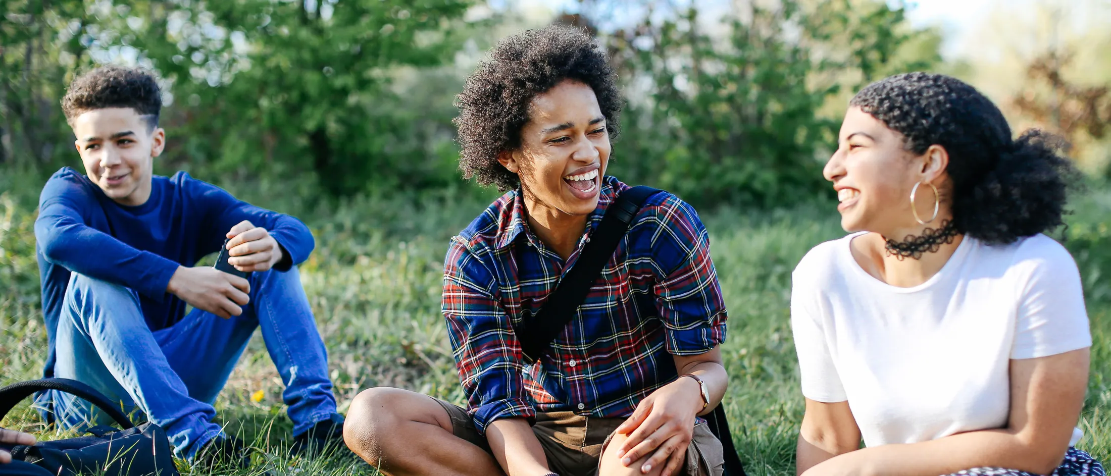 Group of friends sitting on grass, laughing.