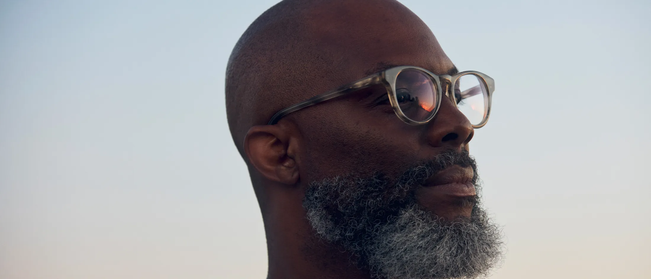 Man gazing into distance during sunset, calm and hopeful expression