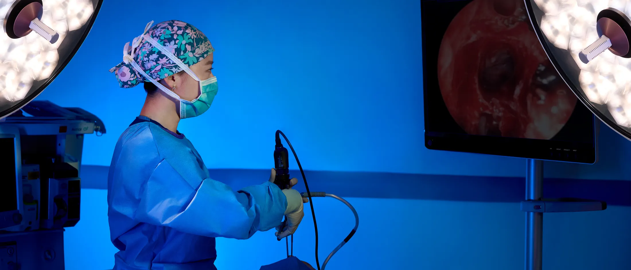 Surgeon performing an endoscopic procedure while viewing an image on a monitor in a brightly lit OR.