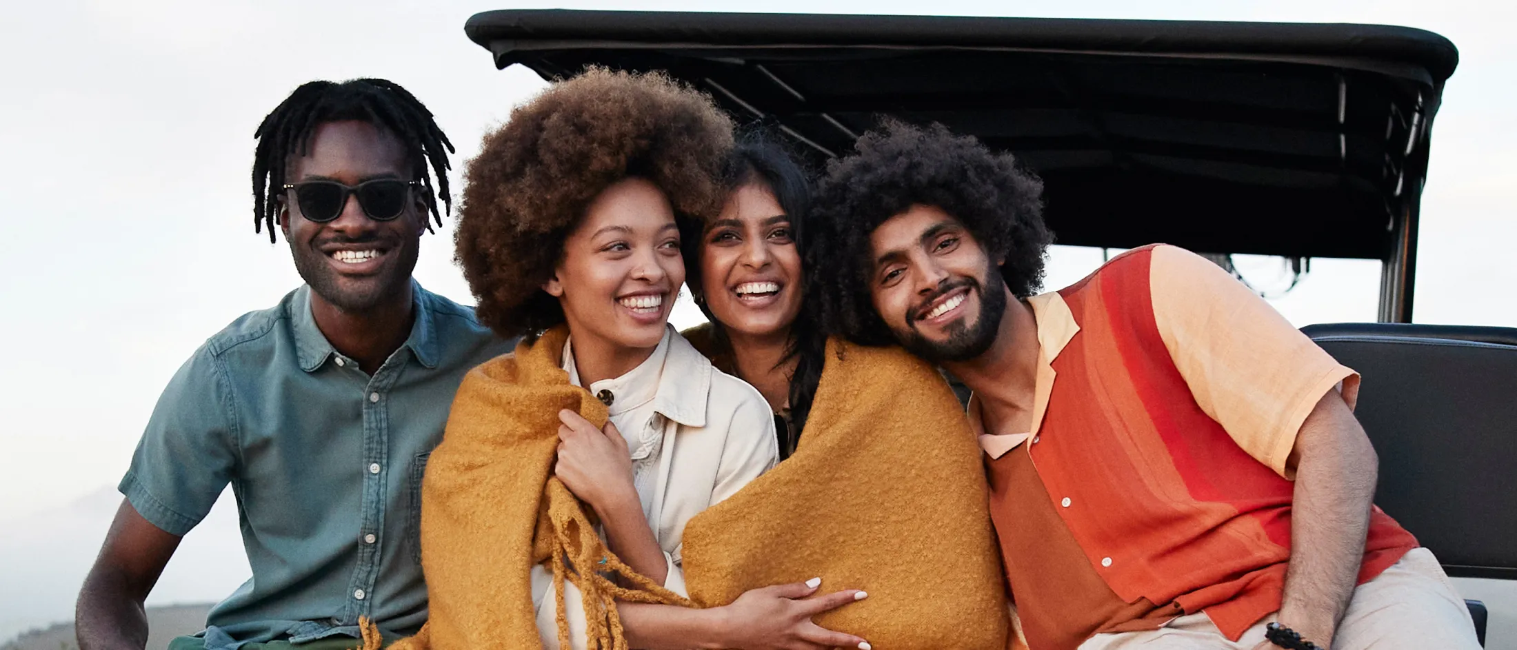 Friends sitting together on a vehicle in a scenic landscape.