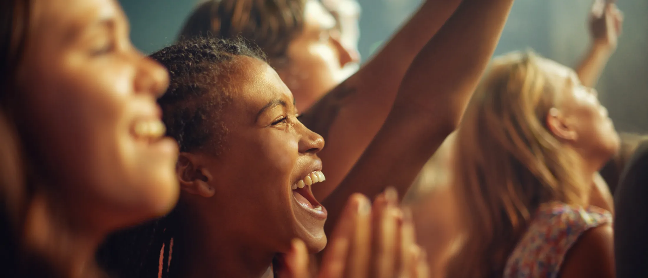 Group of excited people cheering and smiling at a concert or live event.