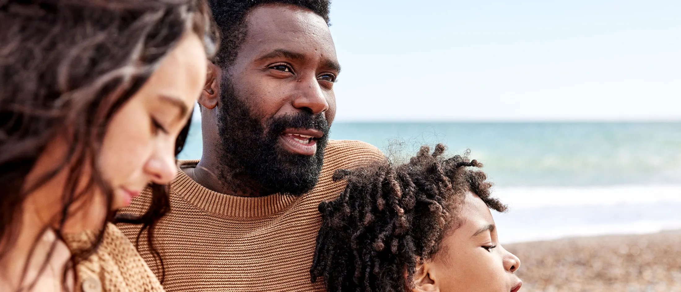 Family sitting on a beach together, enjoying a calm day by the ocean.