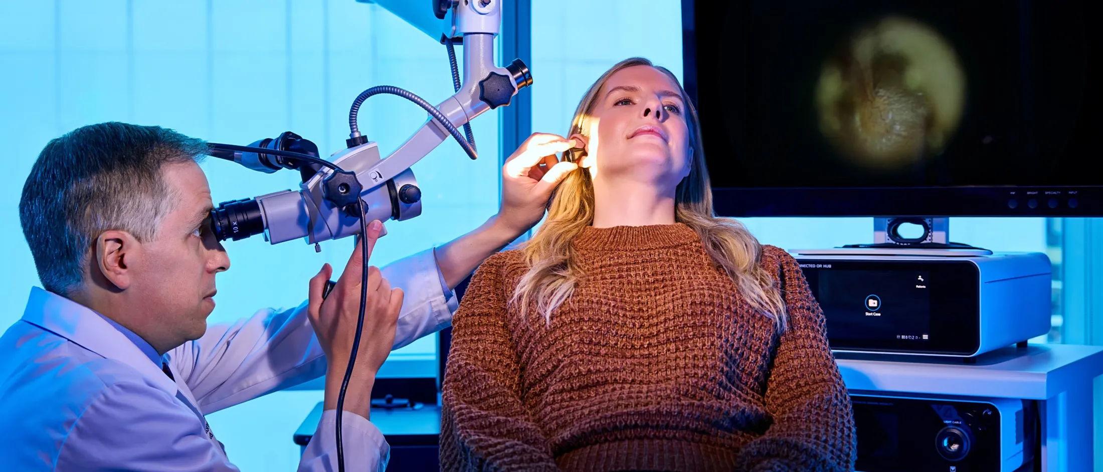 Doctor in white coat using ultrasound device on a patient's neck.
