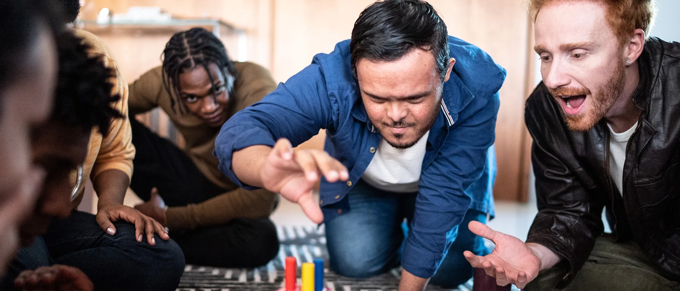 Group of friends enthusiastically playing a tabletop game together on the floor.