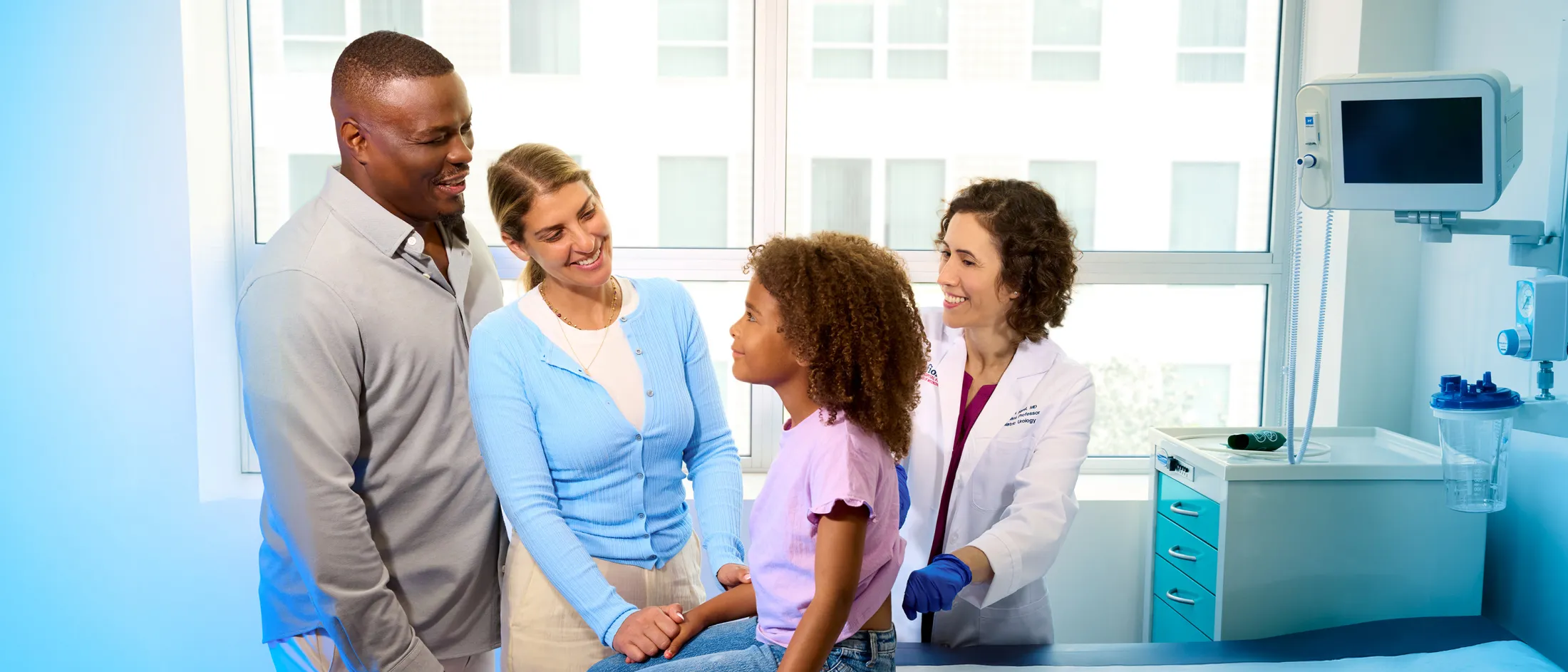 Smiling pediatrician examining a young girl in a clinic while her parents look on supportively.