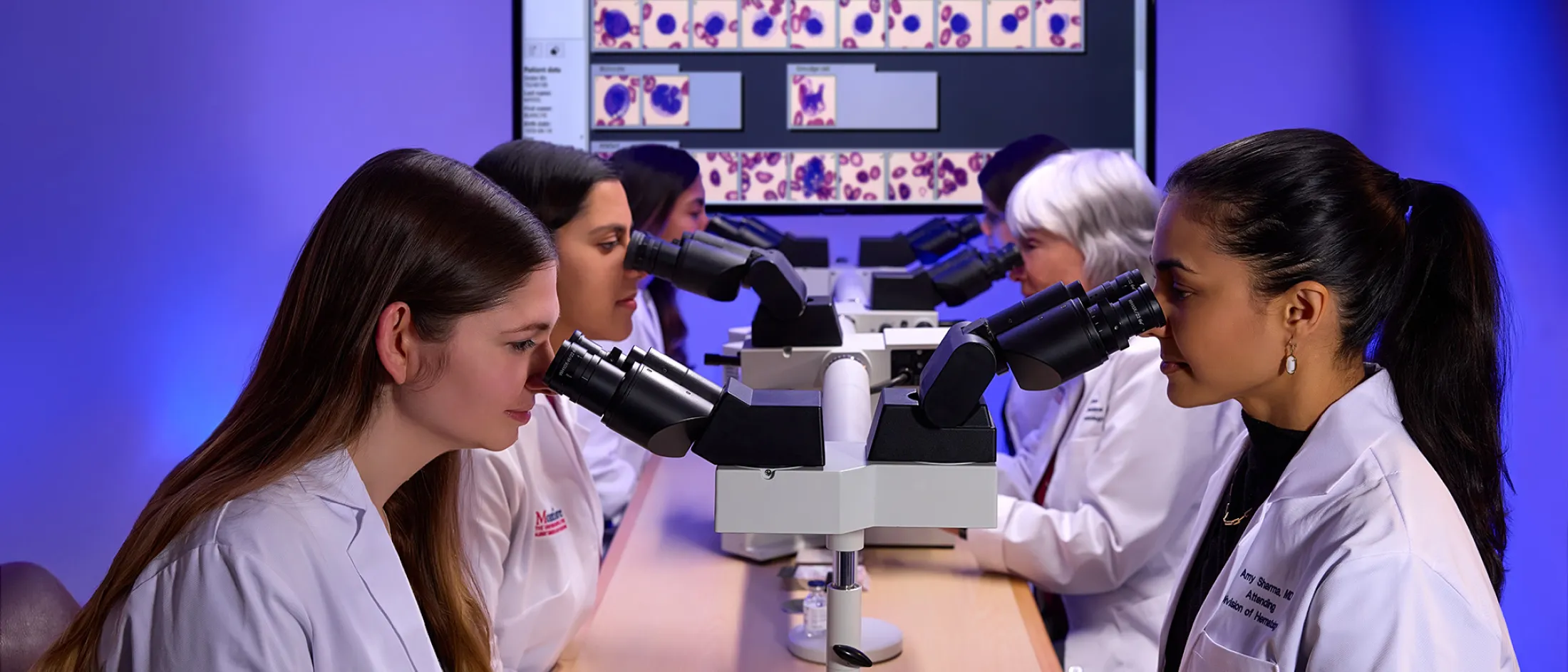 Medical students and faculty at Montefiore Einstein examine blood cell samples through microscopes during a hematology lab session.