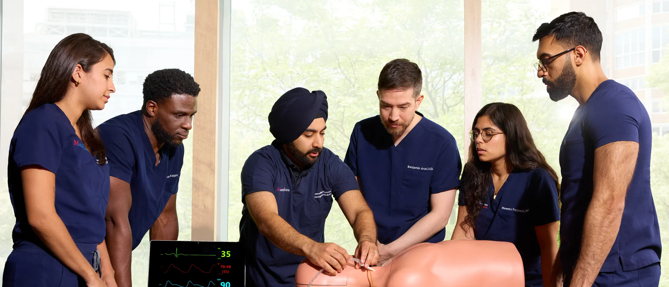 Group of emergency medicine residents practice intubation on a simulation mannequin during a clinical skills session.