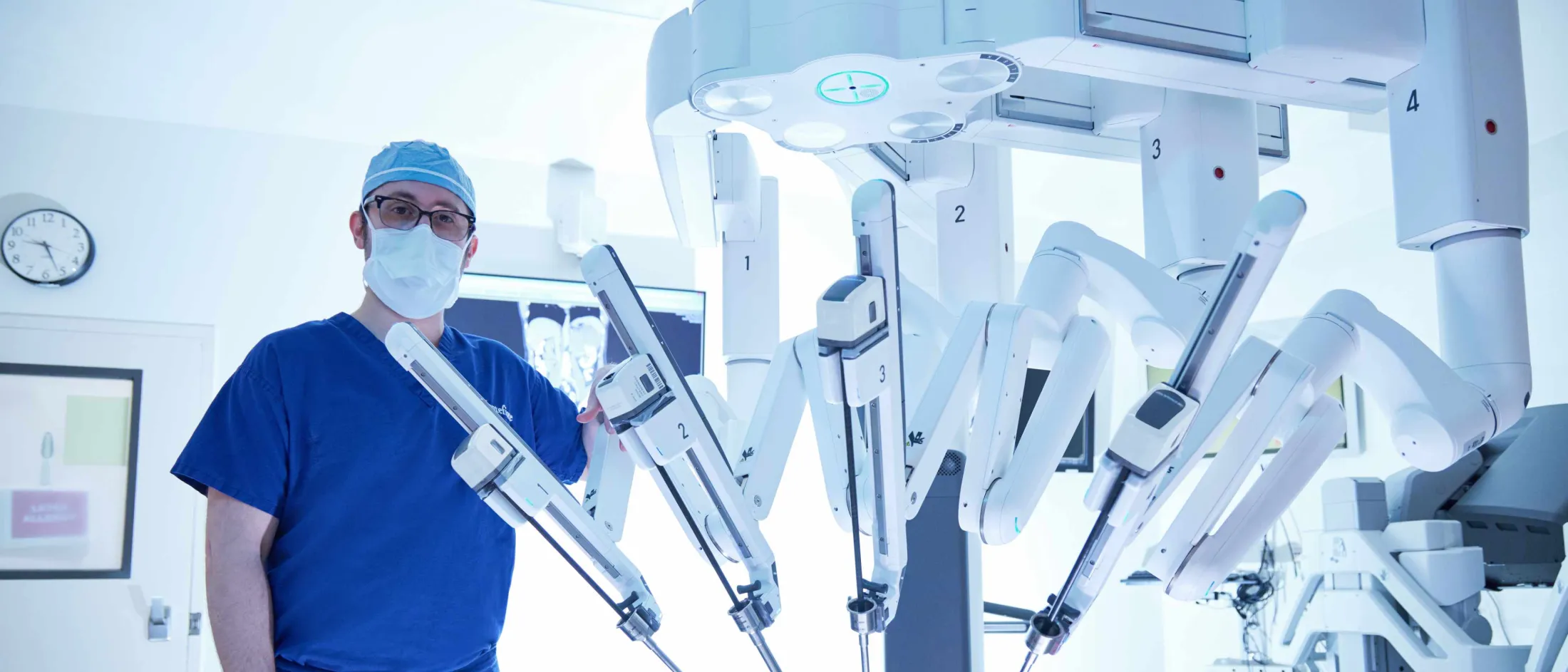 Doctor posing next to a Davinci Robot surgical instrument