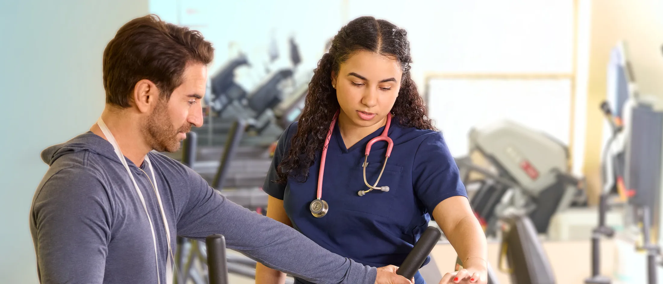 Man working with a female clinician in a rehabilitation gym.