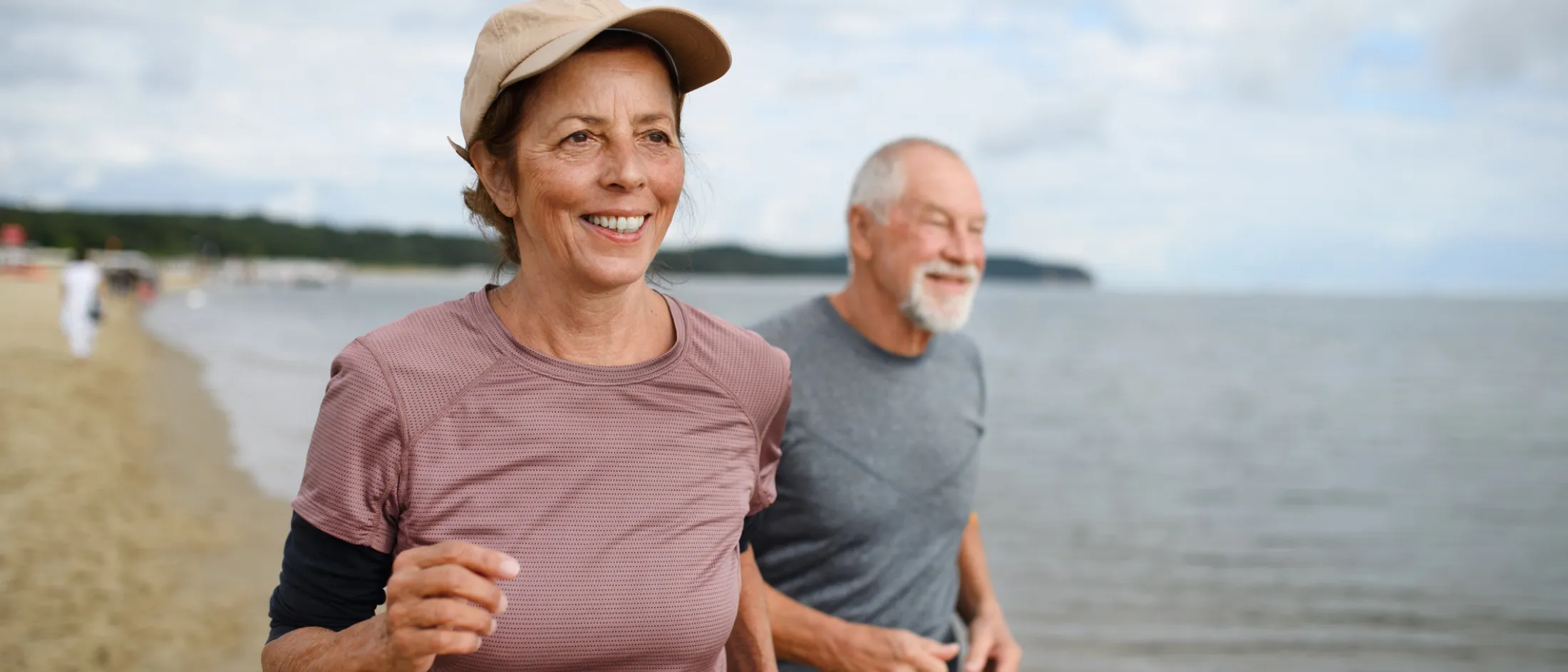 Older couple jogging along the shoreline on a cloudy day