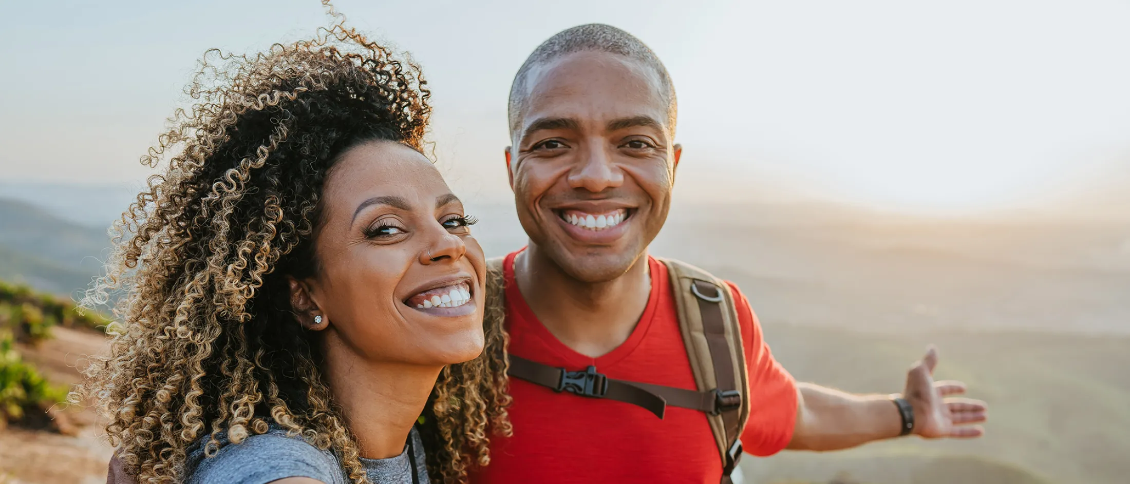 Smiling couple hiking on a mountain trail taking a selfie.